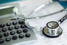 Image of Stethoscope on top of financial papers and calculator